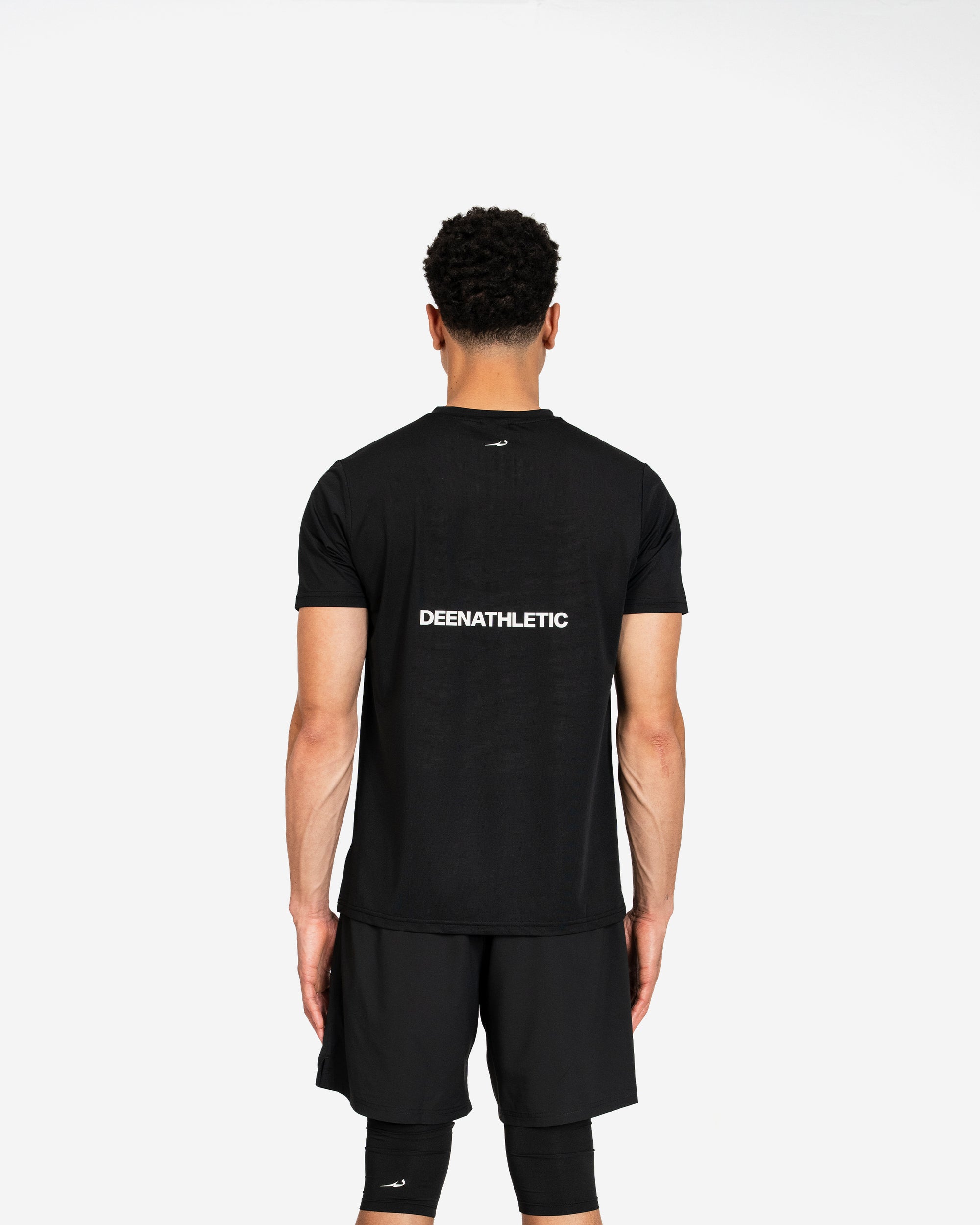 Person wearing a black athletic outfit with 'DEENATHLETIC' branding on the back against a white background