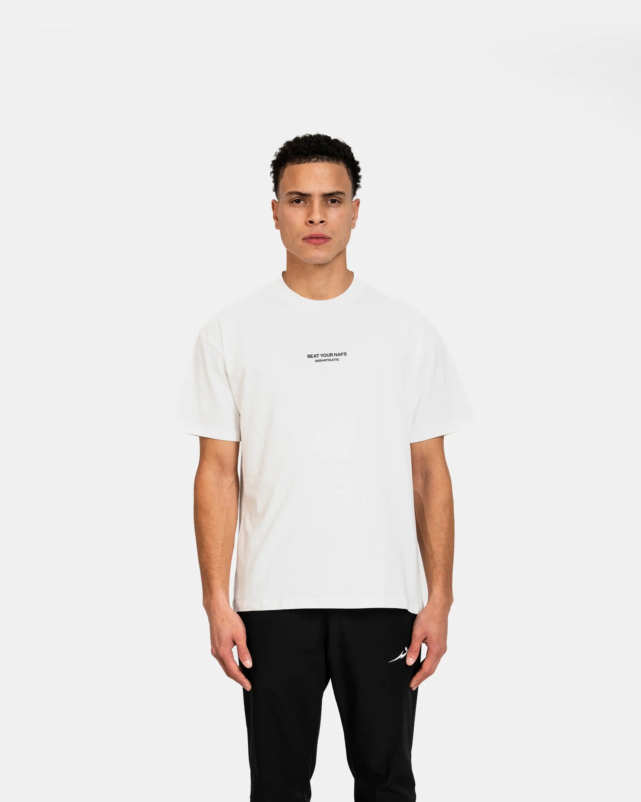 Person wearing a white t-shirt with a small logo on a plain background