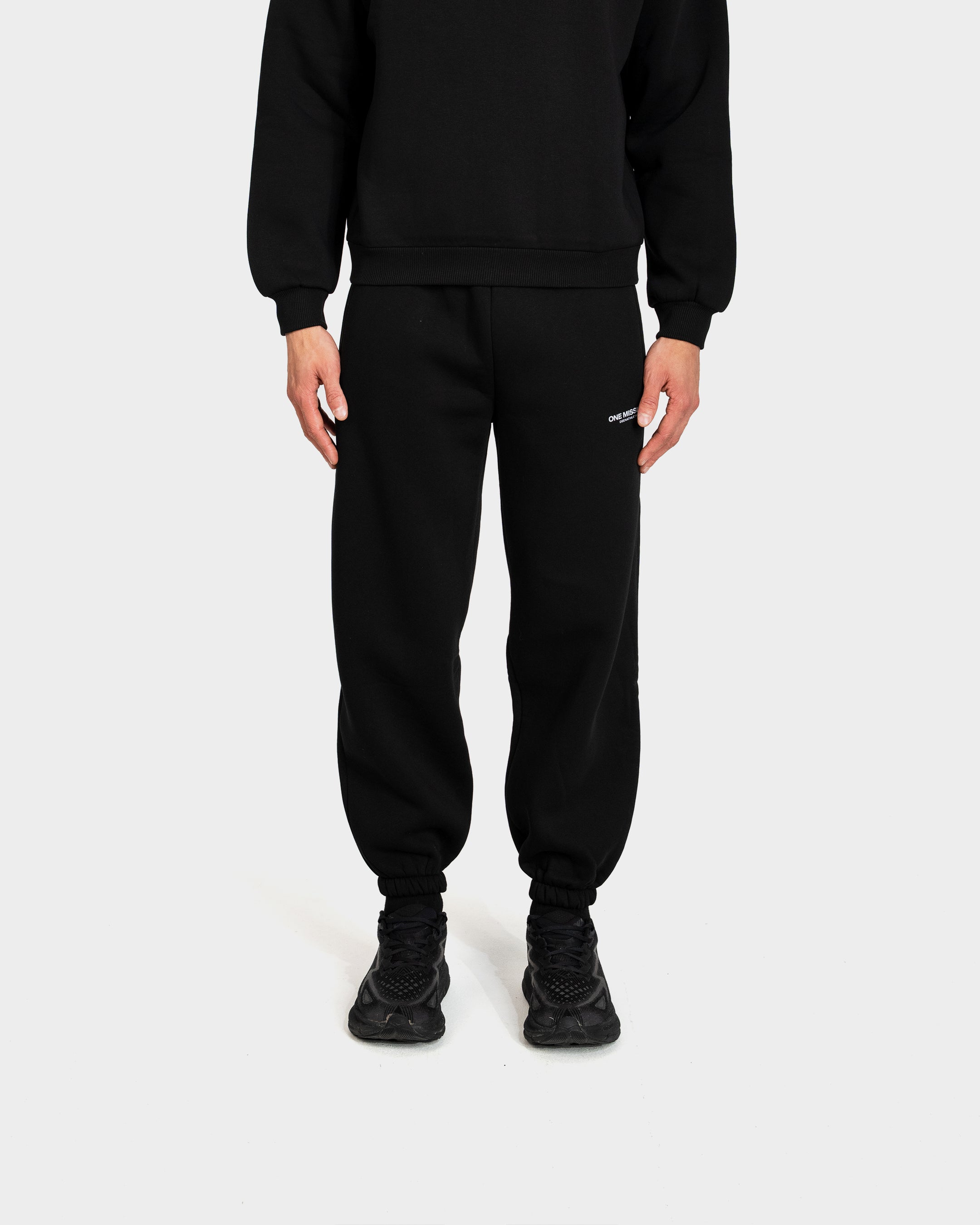 Person wearing a black tracksuit on a white background