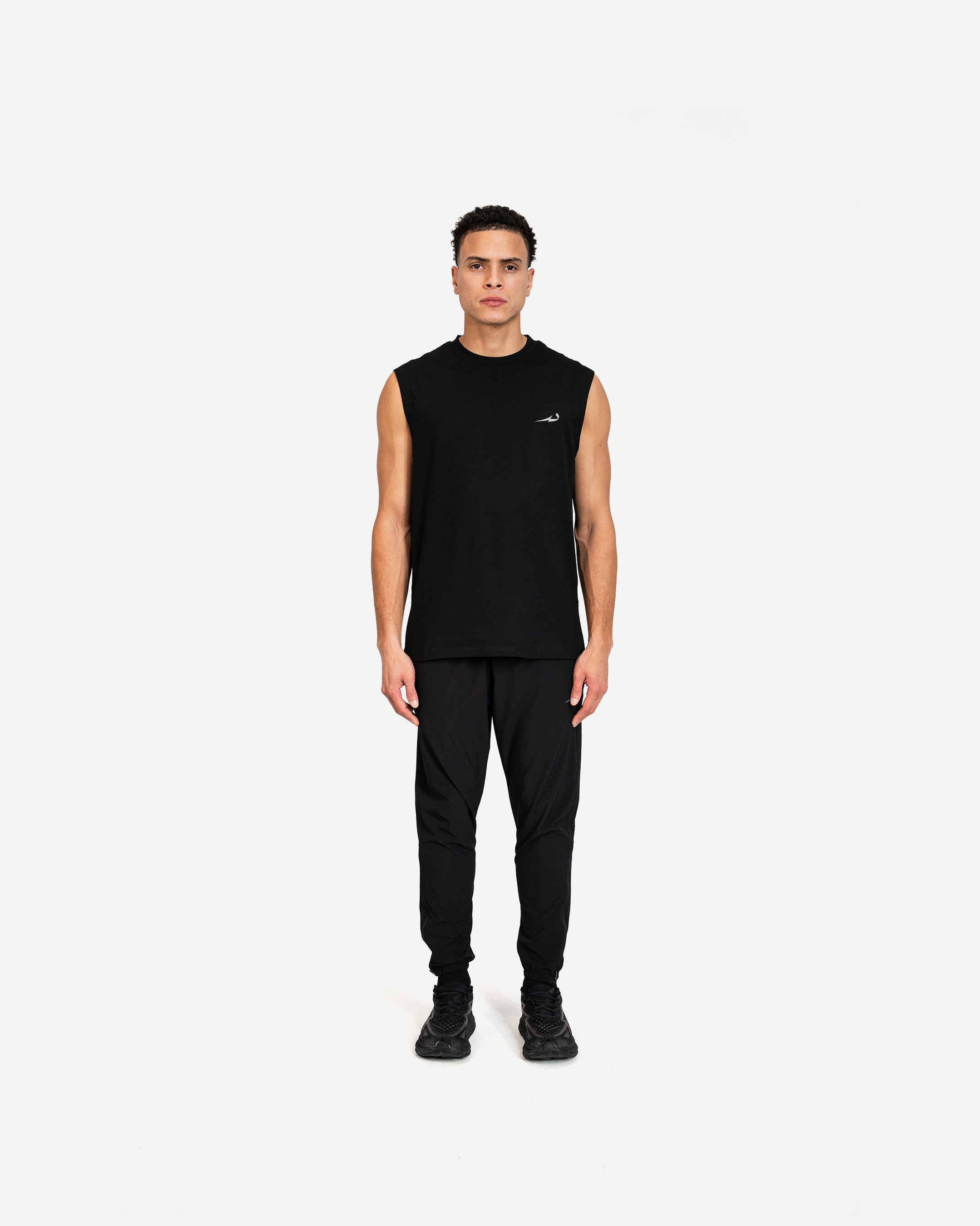 Person wearing a black sleeveless Deenathletic tank top and pants on a white background