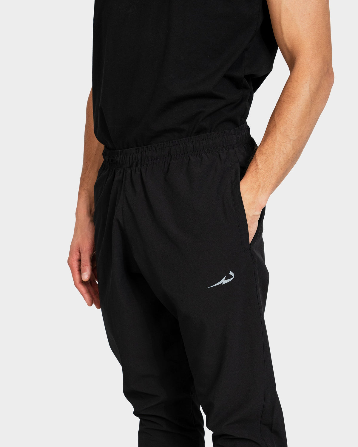 Person wearing black Deenathletic training pants with a logo on a light grey background