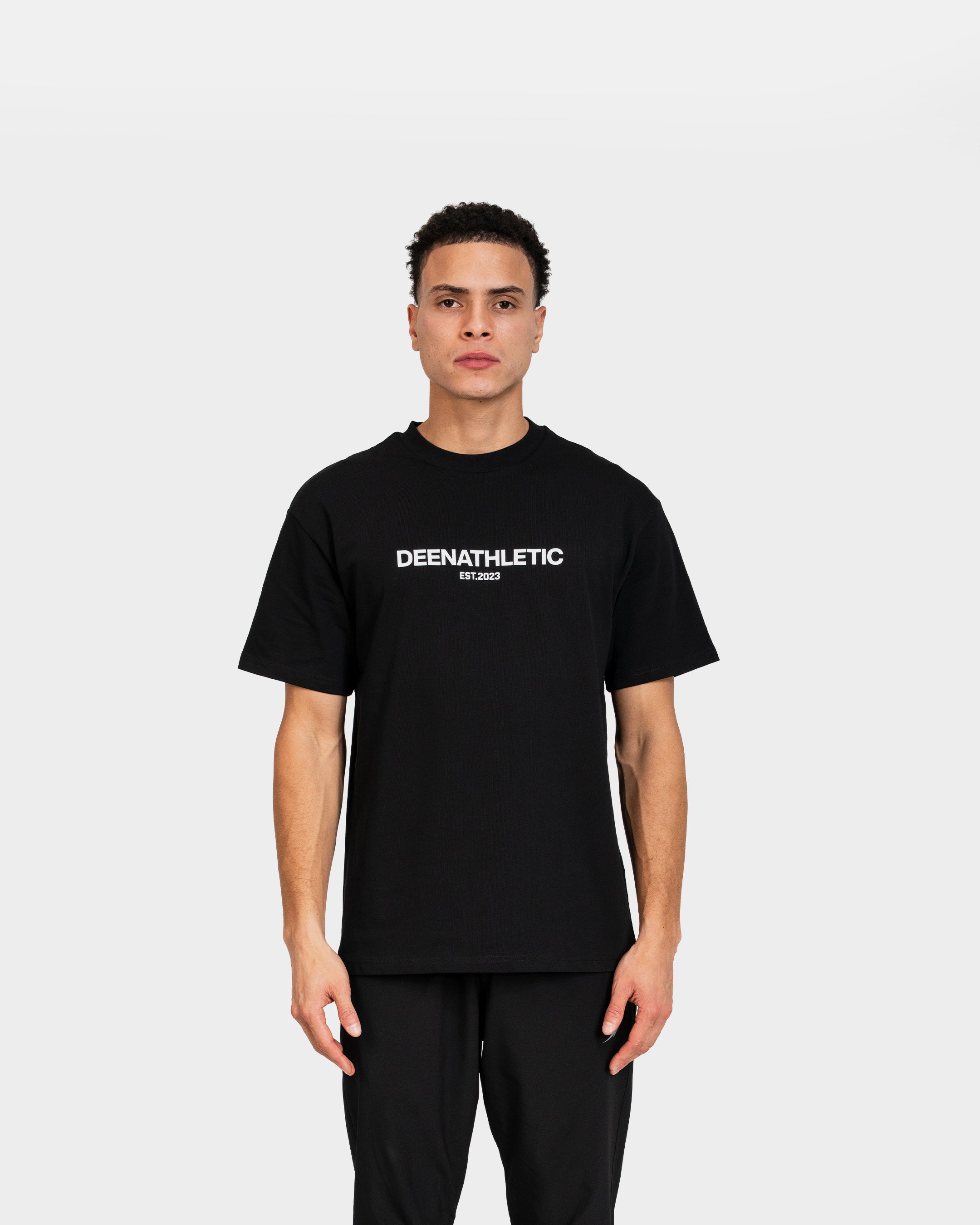 Person wearing a black t-shirt with 'DEENATHLETIC' logo on a white background