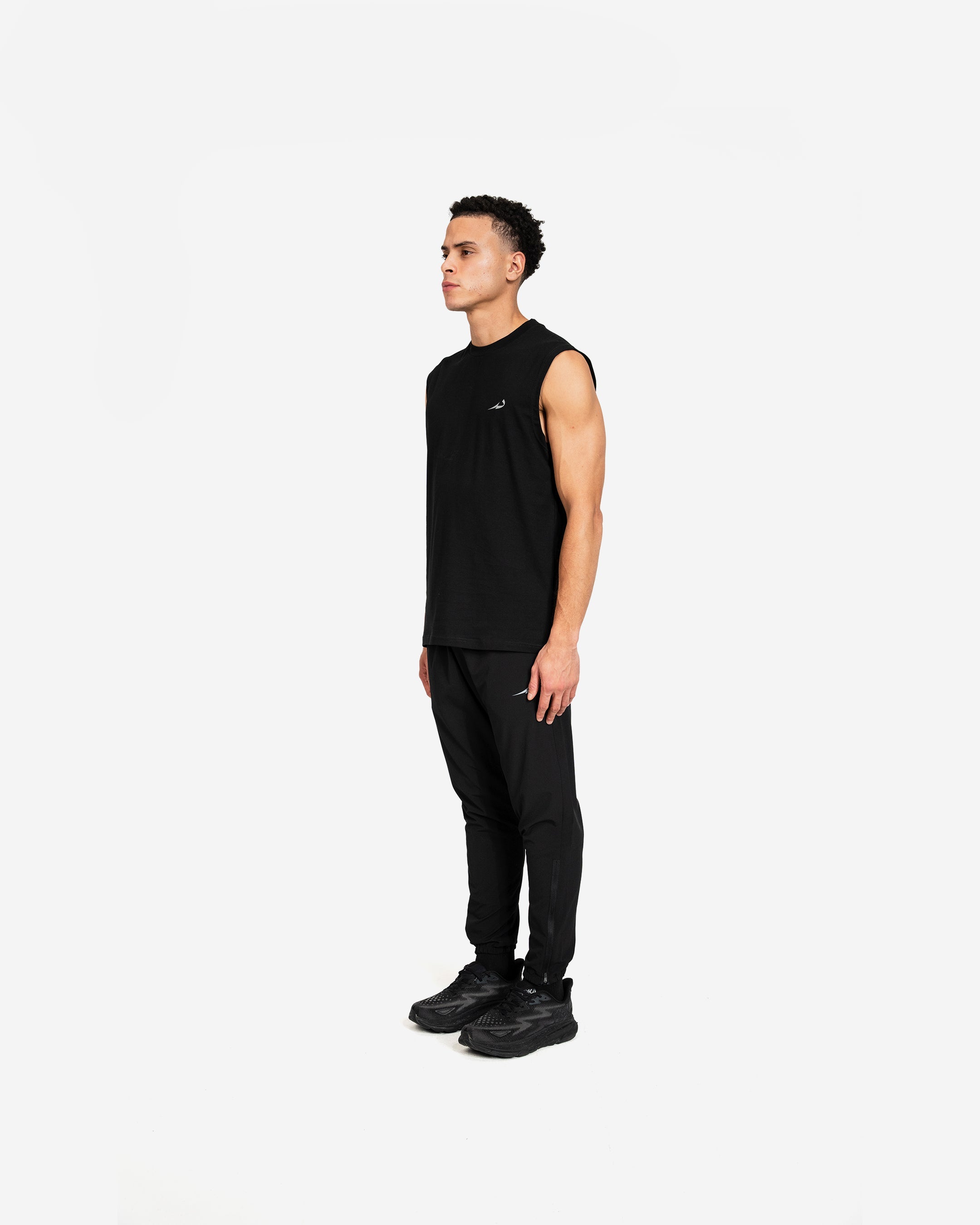 Man wearing a black sleeveless Deenathletic tank top and pants on a white background