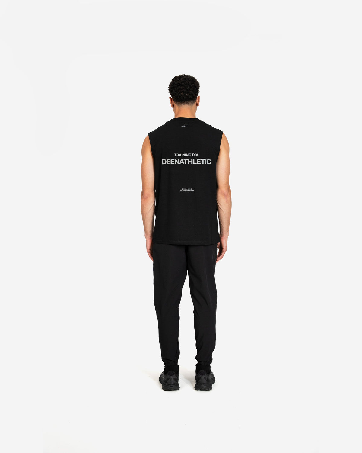 Person wearing a black sleeveless shirt with 'DEENATHLETIC' branding on the back, standing against a white background.