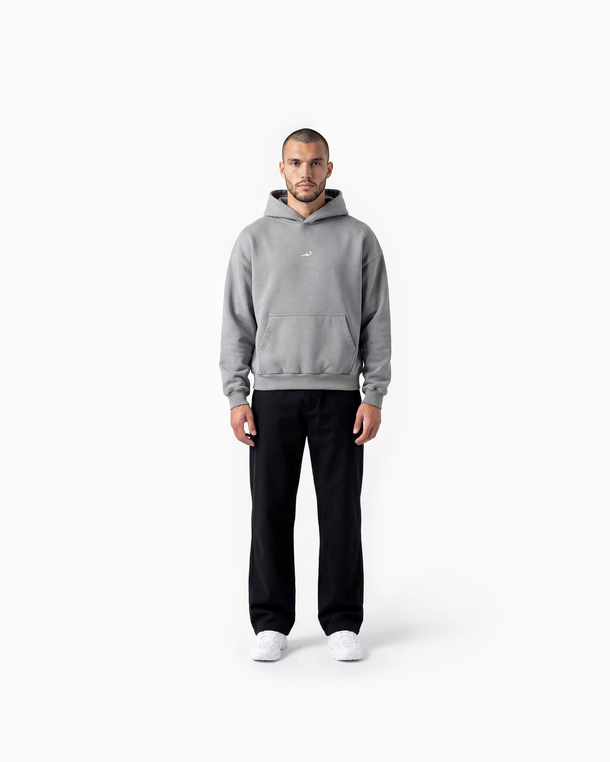 Man wearing a grey hoodie and black pants on a white background