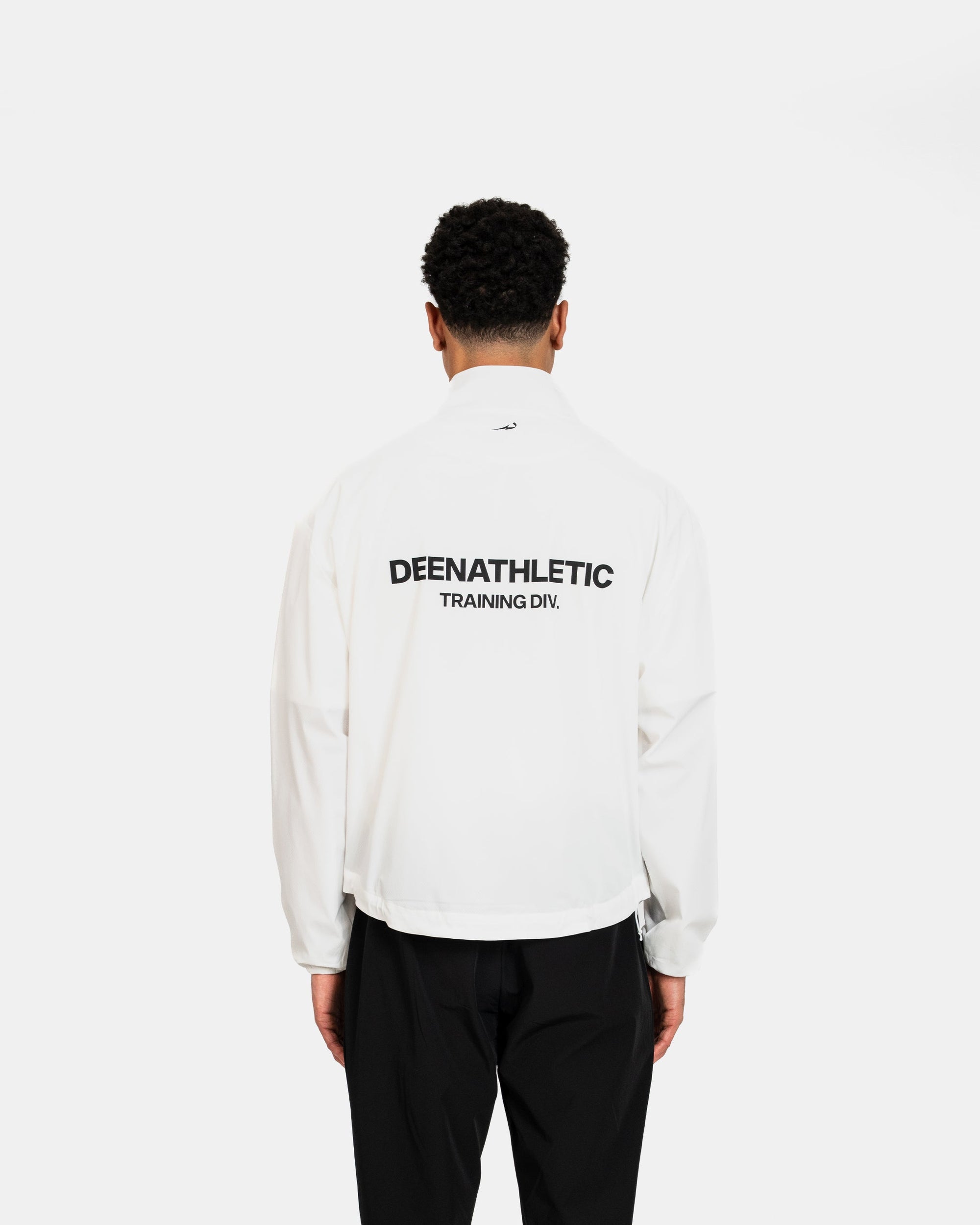 Person wearing a white jacket with 'DEENATHLETIC' branding on the back, standing against a white background.