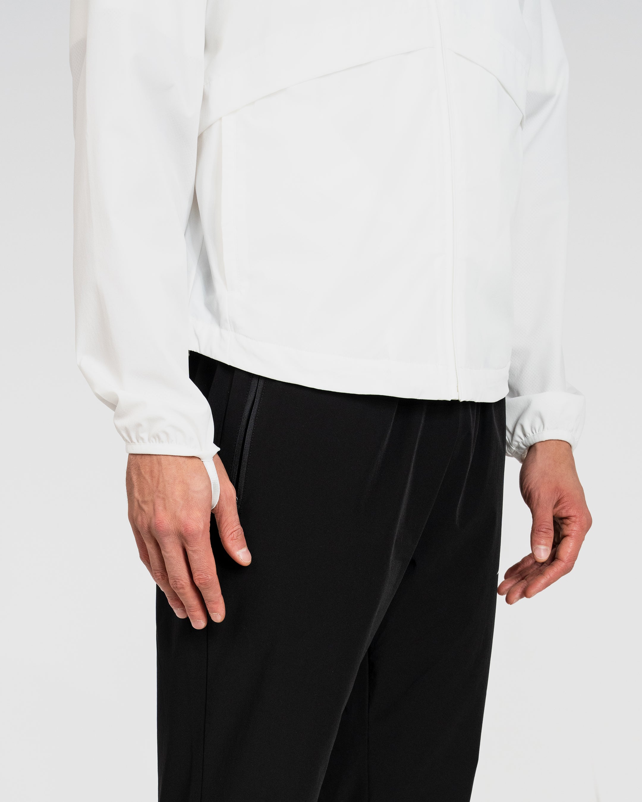 Person wearing a white long-sleeve jacket and black pants on a white background
